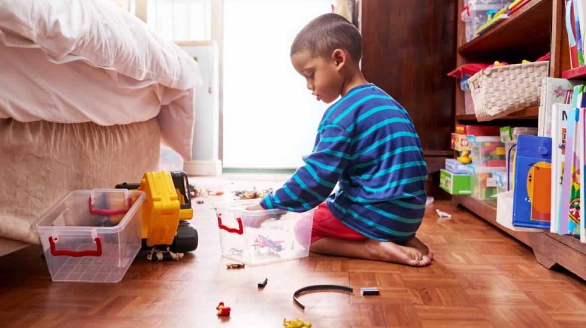 boy cleaning up toys in his room