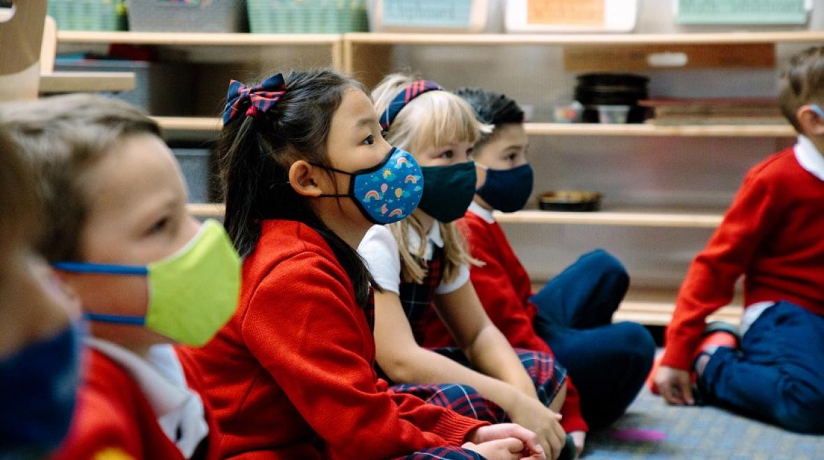 Young Epiphany School students sit on the floor listening attentively