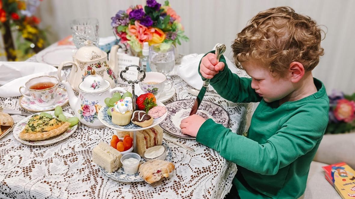 Young child having afternoon tea under flower decorations at Graham's Royal Tea