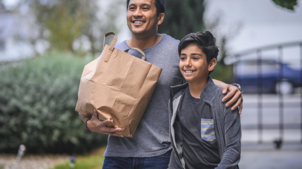 Father and son walking with a paper bag