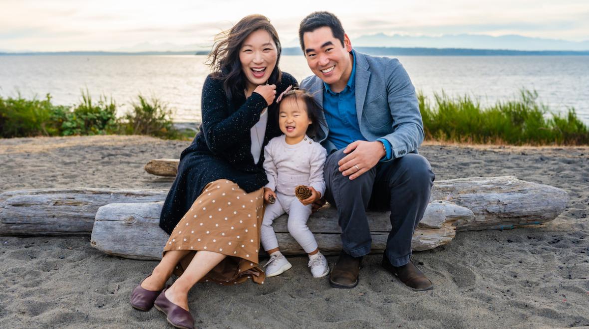 Seattle parents pose with their young daughter on a Pacific Northwest beach