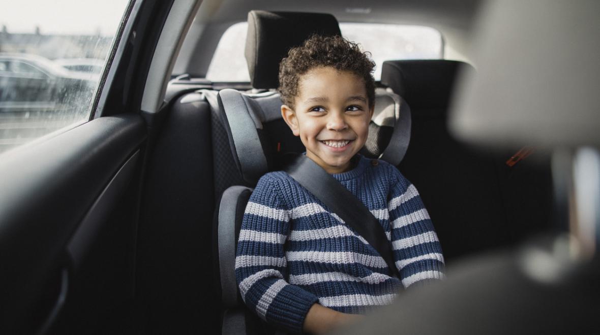 boy smiles in the backseat of a car