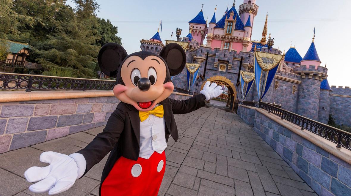 Mickey Mouse welcomes you to Disneyland in front of Sleeping Beauty's castle