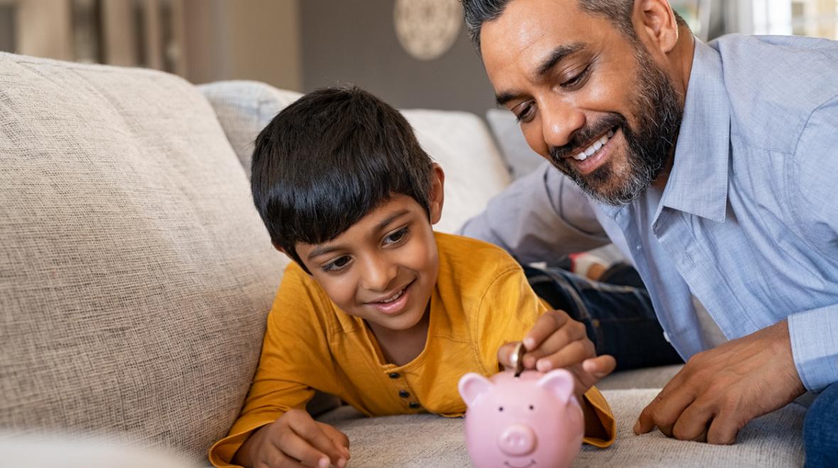 Dad and a son learn about money management with a piggy bank.