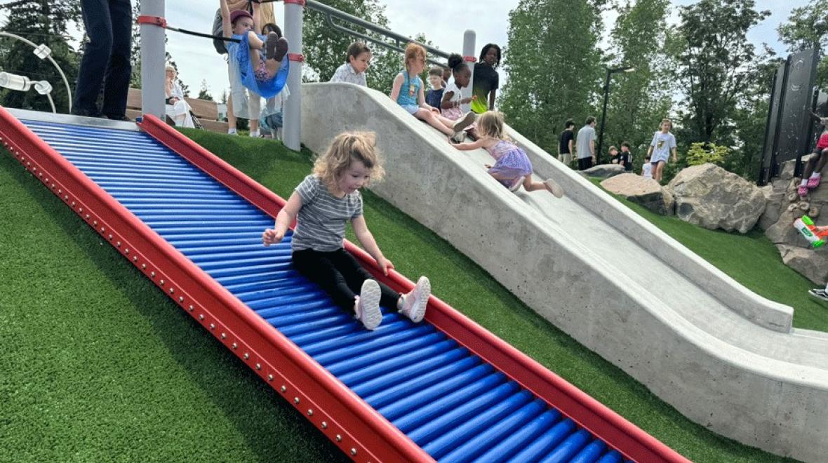 Young girl slides down a roller slide at a new inclusive playground near Seattle