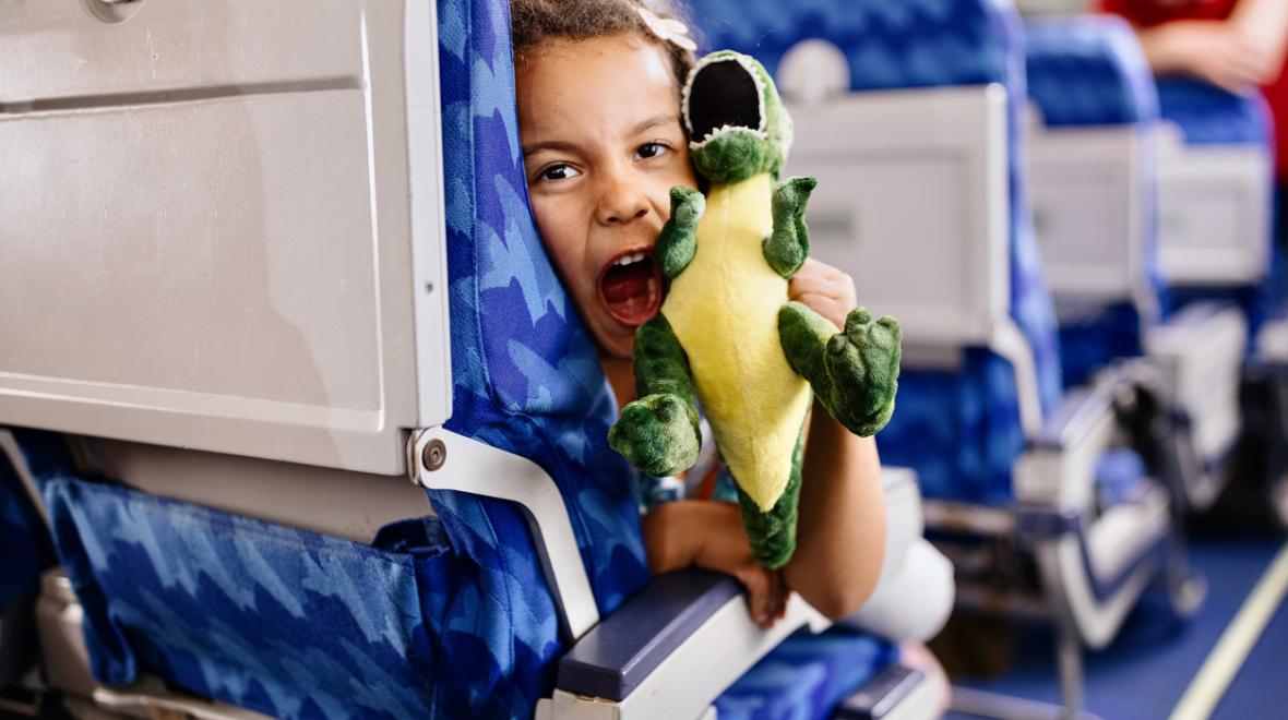 child plays with a stuffed toy on an airplane while traveling with family