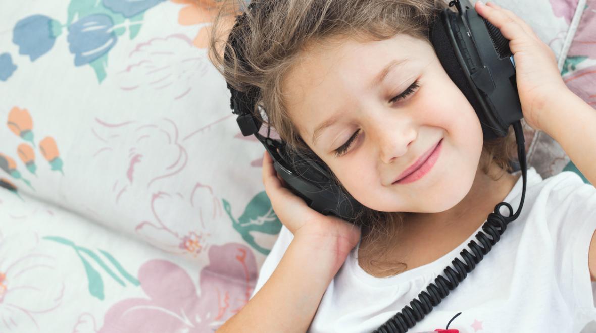 a child wears headphones while happily listening to music from a goody bag CD