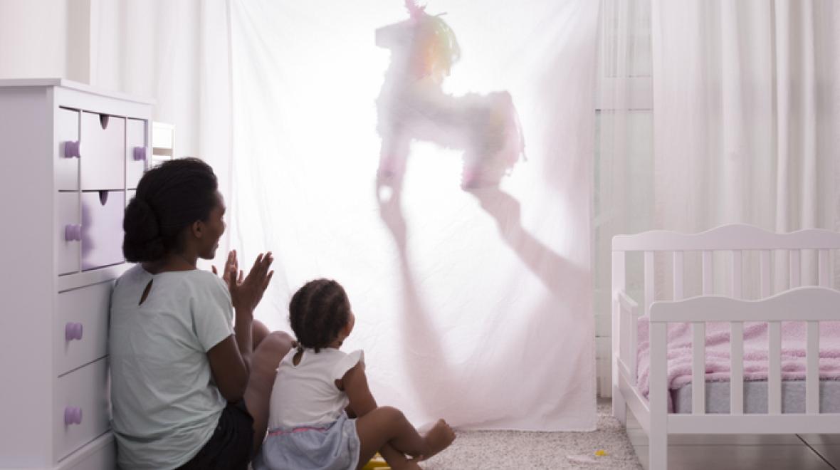 a mom and daughter watch an entertaining home puppet performance