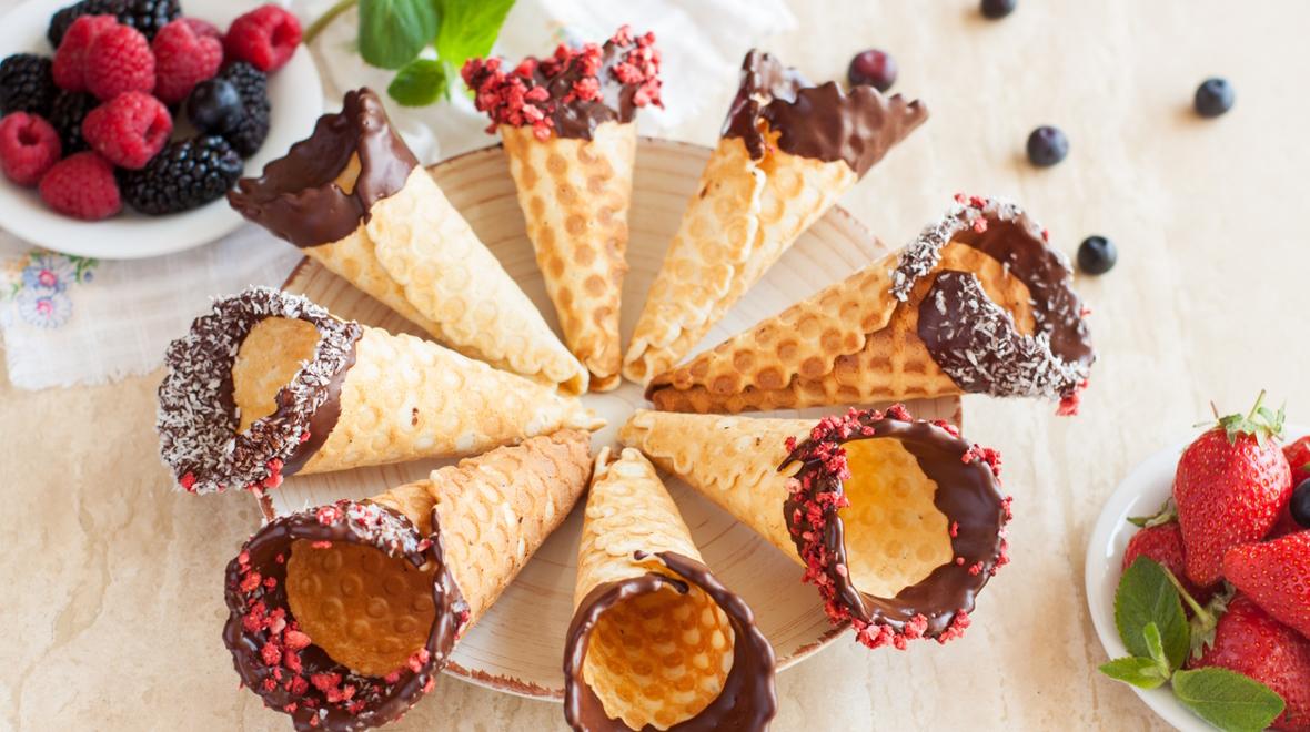 Ice cream cones dipped in chocolate and sprinkles on a plate