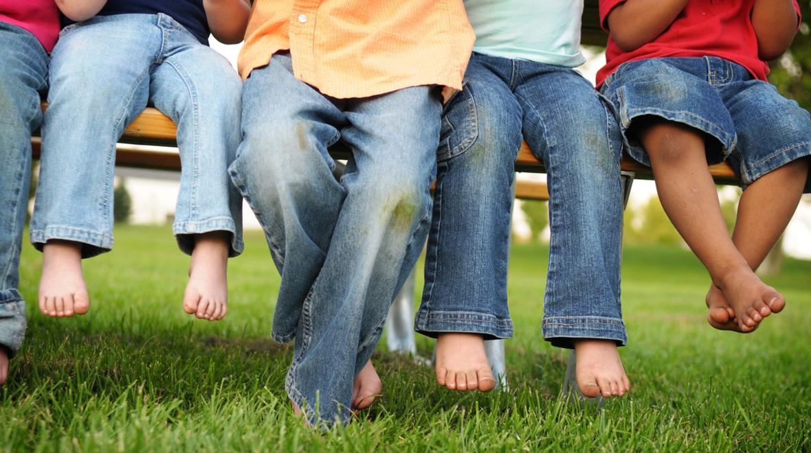 Young children sitting on a bench in the grass all wearing jeans. Target Denim Take Back Event