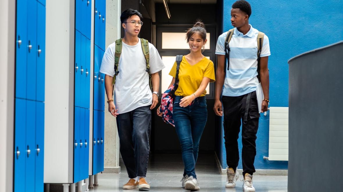 Three high school students walking down a school hallway