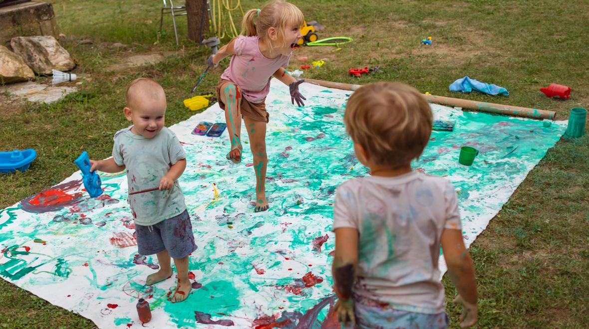Three kids painting and making a mess outside doing a fun messy art project