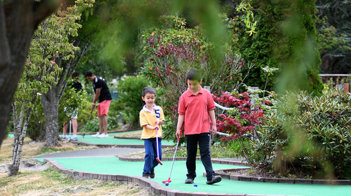 brothers playing mini golf at interbay on a Sunny Seattle day