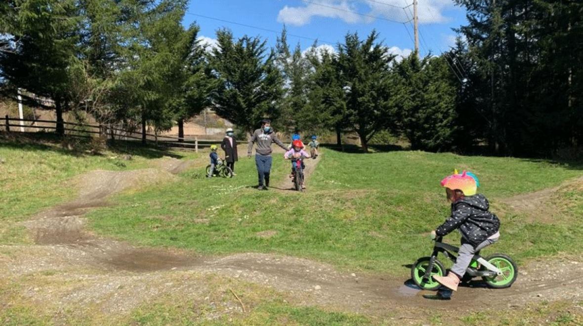 Young girl wearing a bike helmet tries out the pump track at Fisher Creek Park, a Seattle-area pump track