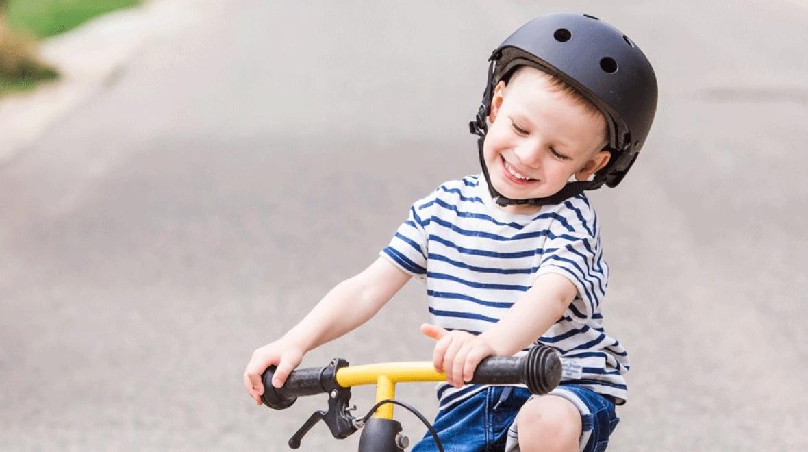 Young boy wearing a bike helmet smiling on his bike at a Seattle-area pump track