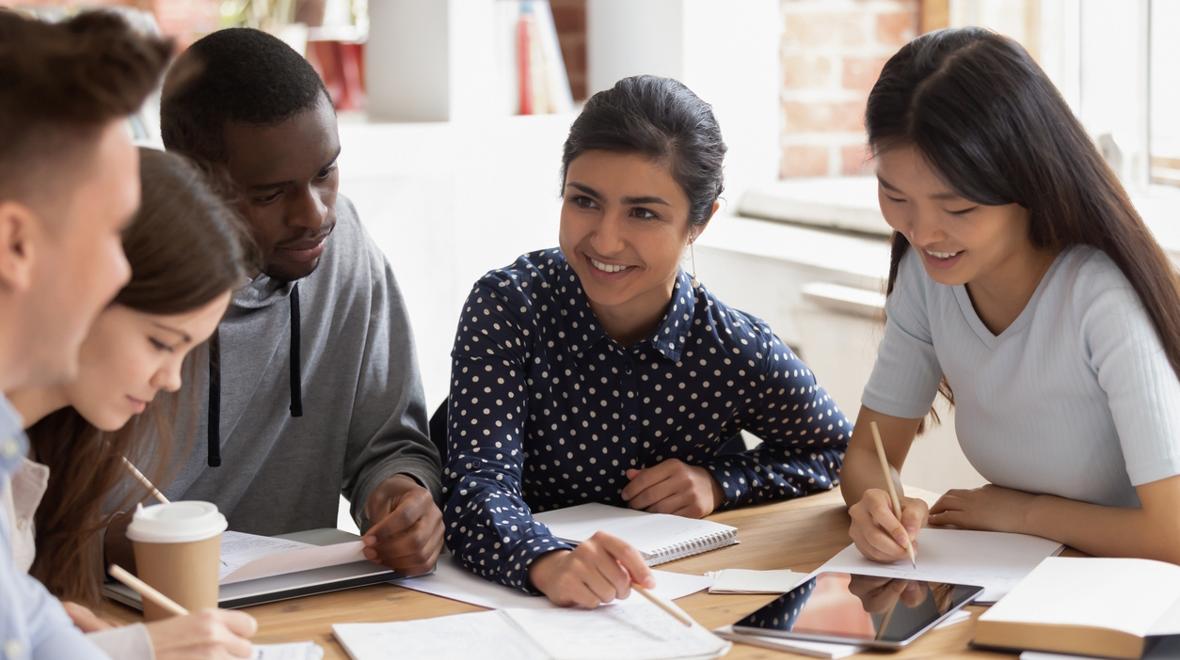 Teenagers sitting around a table with a teen girl as the leader