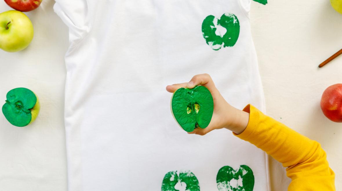 a child uses an apple to make prints