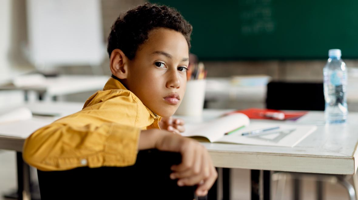 elementary-age student in an empty classroom looking back at the camera