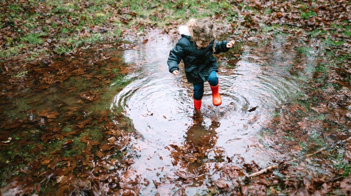 Young girl stomping in a puddle while on a kid-friendly fall hike