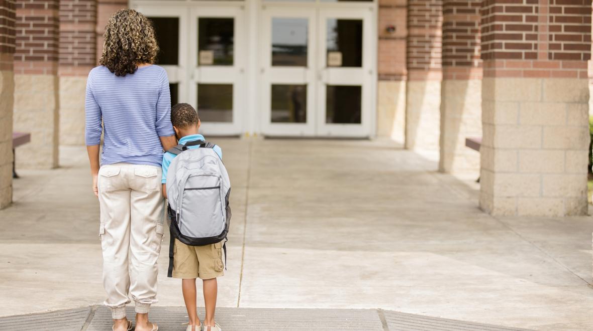 Mom and son standing outside building, child feeling school anxiety