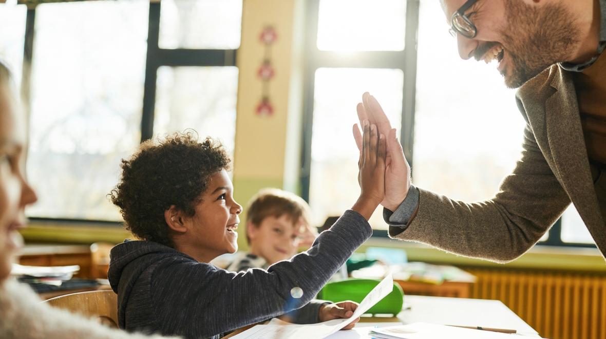 Boy and teacher giving a high five and have a positive student-teacher relationship