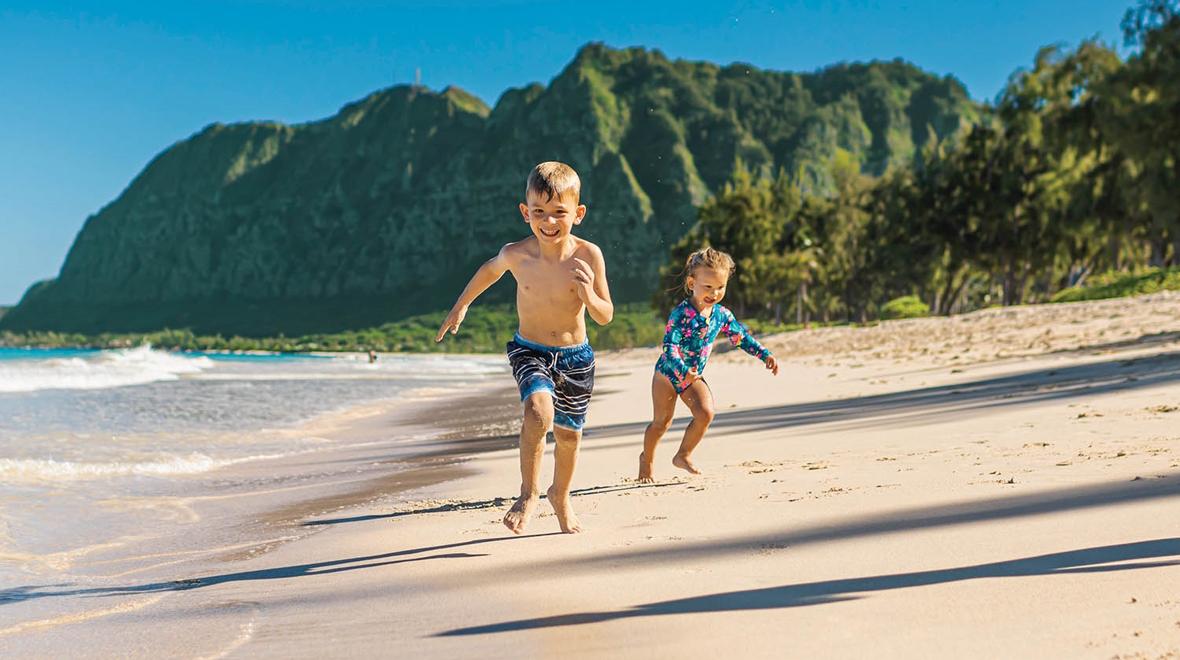 Two kids running on a beach Kauai family vacation things to do 