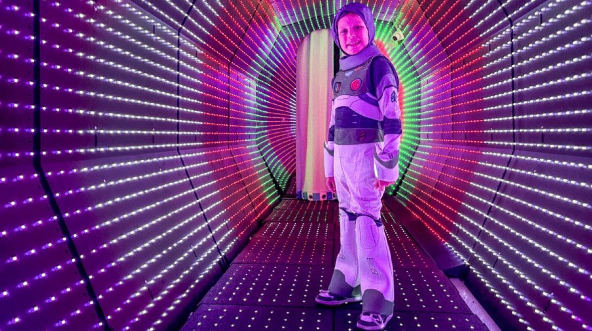 Young boy stands in the light tunnel at Cosmic Carnival in Seattle, a seasonal Halloween event for families