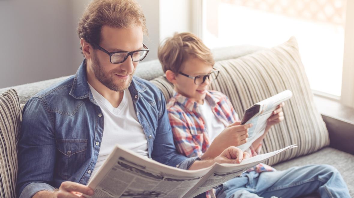 dad and son reading current events in the newspaper