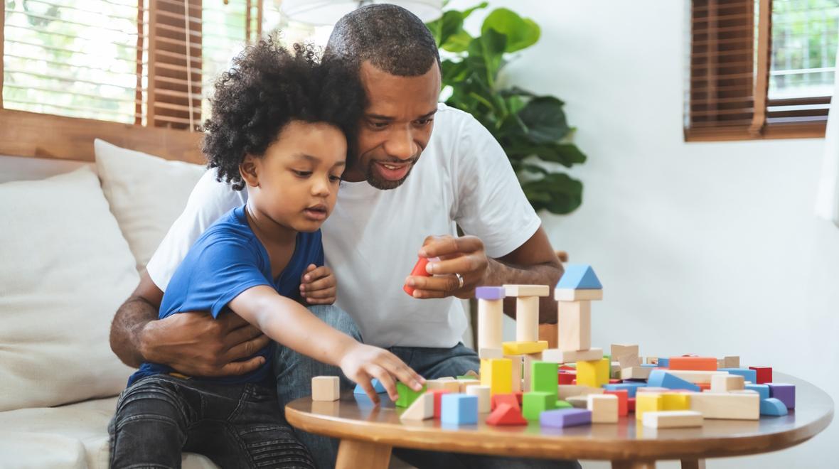 Dad and son having positive experience together playing with blocks on a table