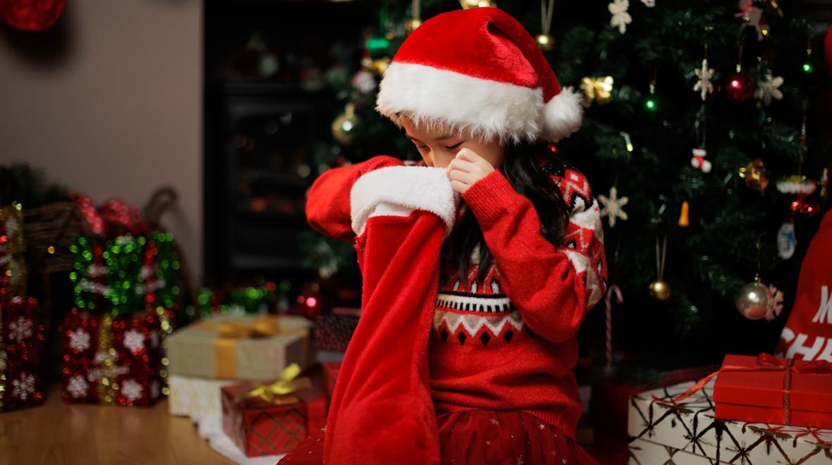 Girl looking in her Christmas stocking for the best stocking stuffers 