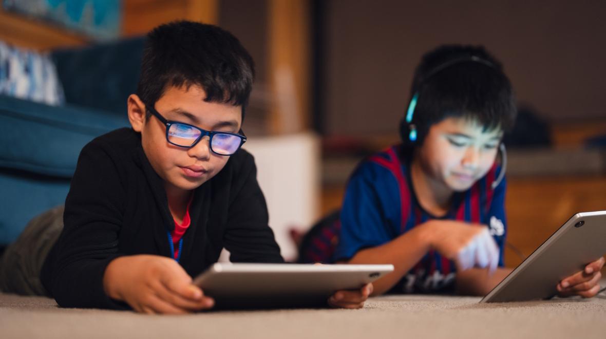 Two boys playing video games on tablets 