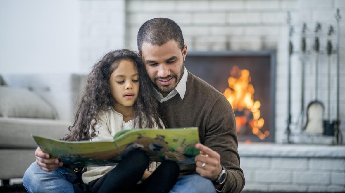 Dad and daughter reading in front of fireplace