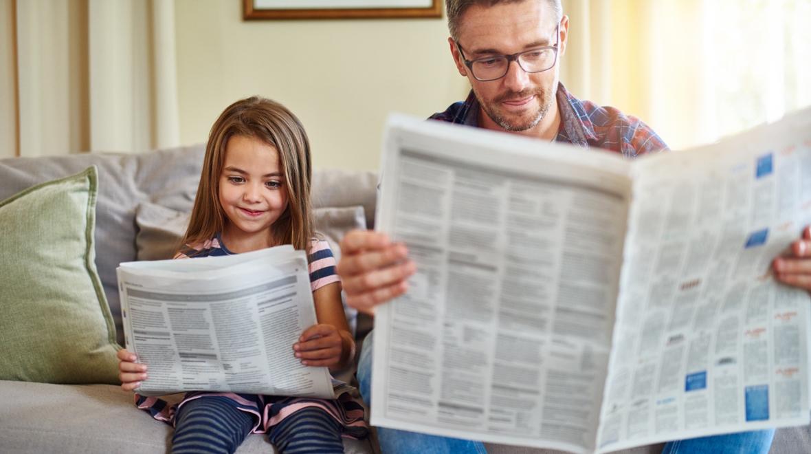 Dad and daughter reading the newspaper together