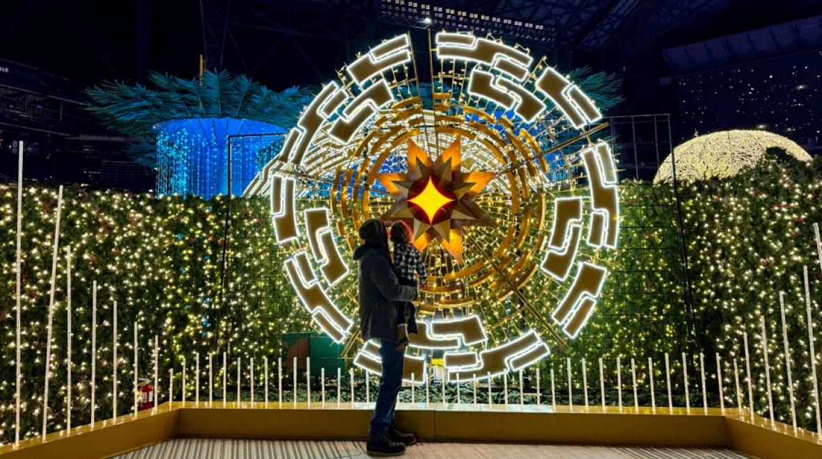 father daughter admiring holiday light display at Enchant Christmas, a seattle attraction with a large light maze and holiday displays