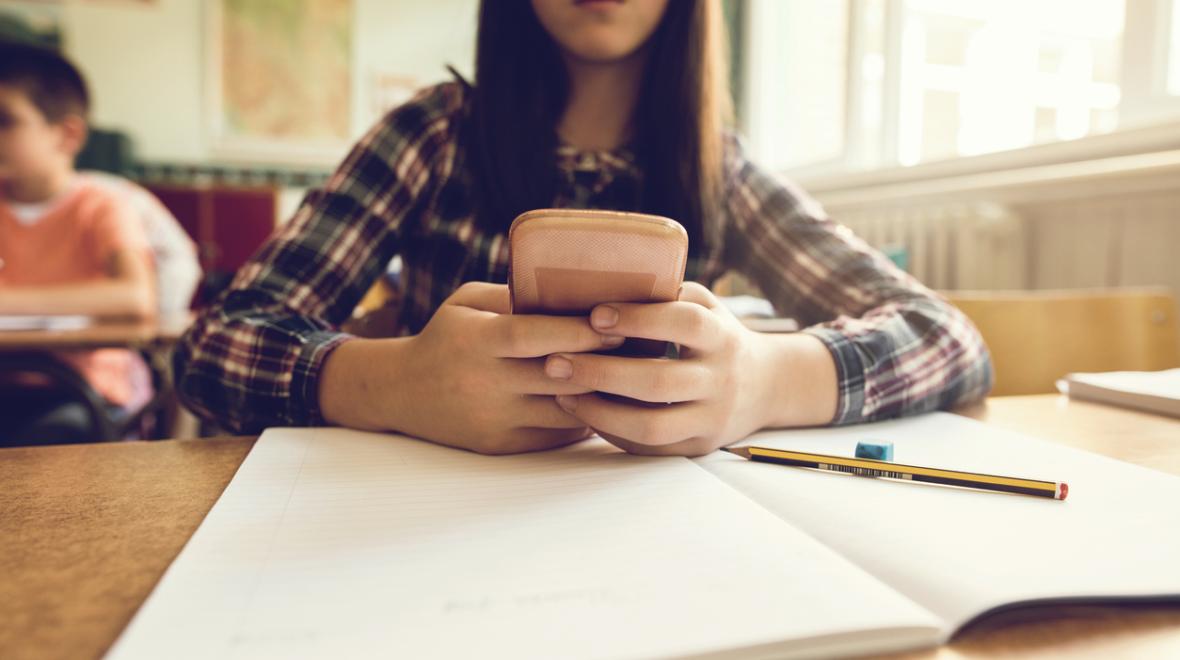 young student looks at her phone in class