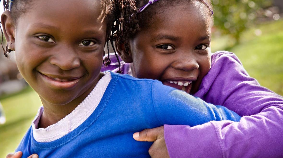 Black History Month events with smiling African American sisters hugging each other. 