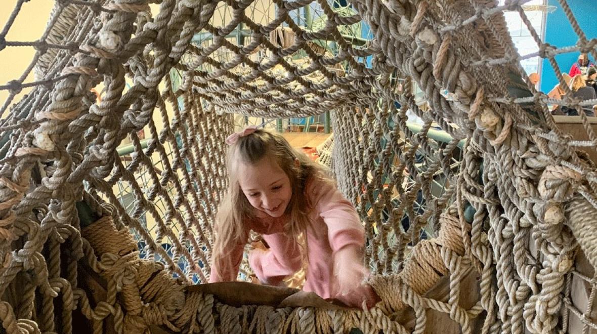 Girl playing in a rope tunnel at the Children's Museum of Tacoma