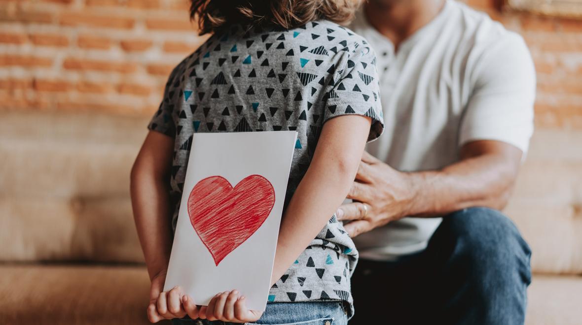 child holding a valentine for their parent behind their back