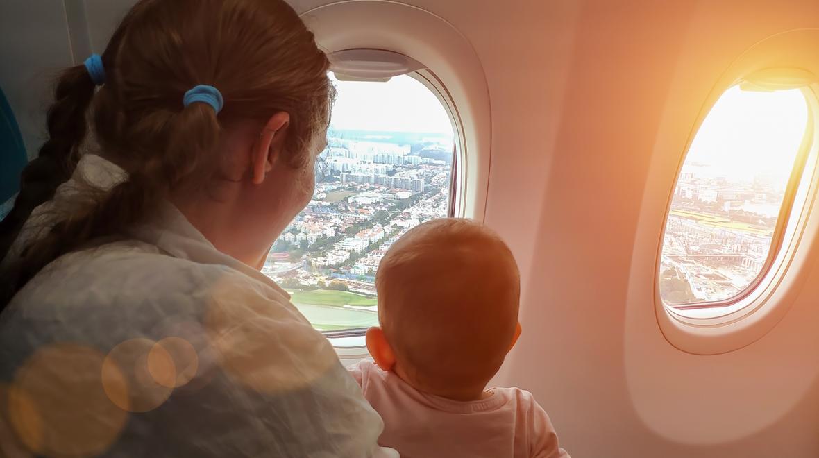 mom and baby on an airplane looking out the window and a city below