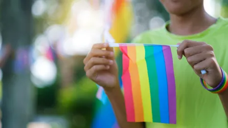a child holds a rainbow Pride flag