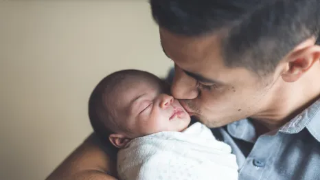 Dad kissing newborn baby