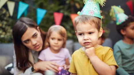 young child looks sad at a birthday party