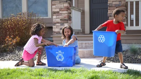 Kids sorting trash into recycling bins with their mom, sustainable living