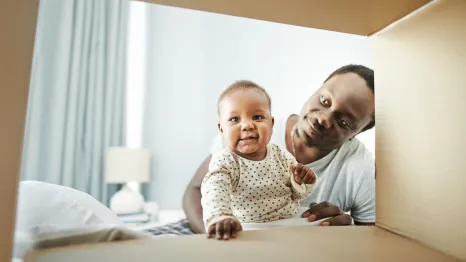 baby looking through an empty baby subscription box sitting in his dad's lap