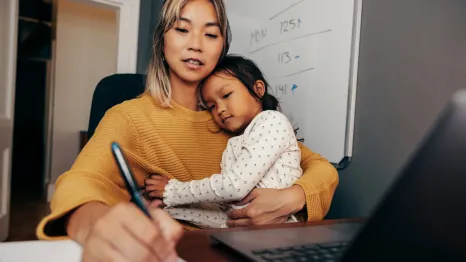 mom working from home with her daughter sitting in her lap