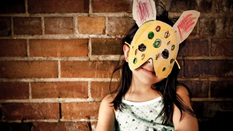 a child wears a DIY mask that she made for an indoor play activity