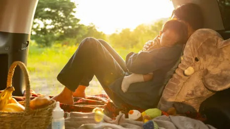 a parent and baby enjoy the summer sunset while car camping