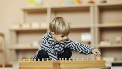 child plays in a Montessori playroom featuring low shelves and simple toys