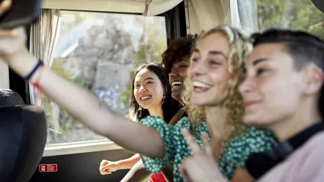 Teens riding the bus and having fun together on a outing for tween and teens