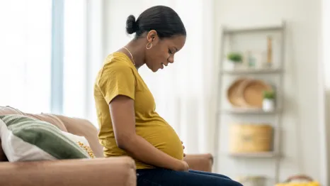 Pregnant woman looks down at her stomach